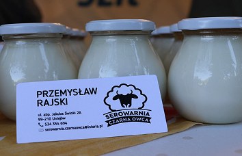 Wizytówka Przemysława Rajskiego na tle słoików z nabiałem