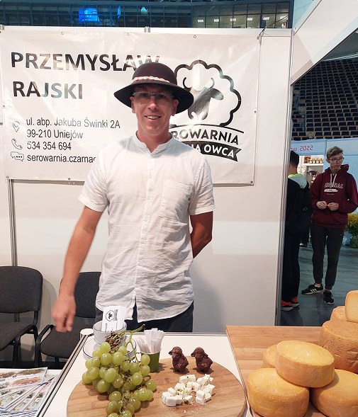 Przemysław Rajski przy stoisku Serowarni Czarna Owca z serami